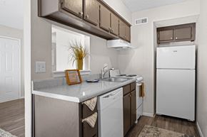 Norman apartment for rent - kitchen area with white refrigerator and brown cabinets at Diamond Creek Apartments, Norman, Oklahoma
