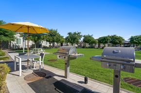 Laveen apartment for rent - a patio with two bbq grills and a table with an umbrella at Sienna at South Mountain Apartments, Laveen, Arizona