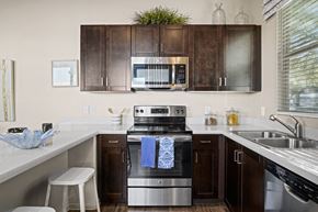 Queen Creek apartment for rent - a kitchen with stainless steel appliances and dark wood cabinets at Olive Queen Creek Apartments, Queen Creek, 85142
