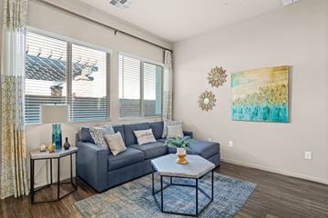 Queen Creek apartment for rent - A living room with a grey couch, a small table, and a painting on the wall.
