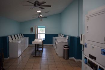 An empty laundry room with washing machines and a ceiling fan
