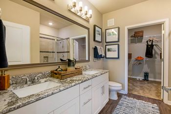 A bathroom with a marble countertop and a large mirror above it.