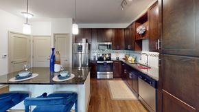 Winter Springs apartment for rent - a kitchen with dark wood cabinets and stainless steel appliances at Integra 360 Apartments, Winter Springs