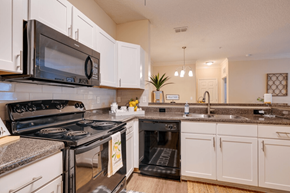 Jacksonville apartment for rent - a kitchen with white cabinets and black appliances at Magnolia Village Apartments, Jacksonville
