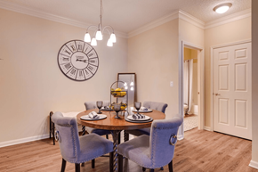 Jacksonville apartment for rent - a dining room with a table and chairs and a clock on the wall at Magnolia Village Apartments, Florida 32207