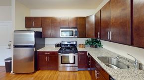 Riverdale apartment for rent - a kitchen with dark wood cabinets and a granite countertop at The Reserve at Riverdale, Riverdale, NJ