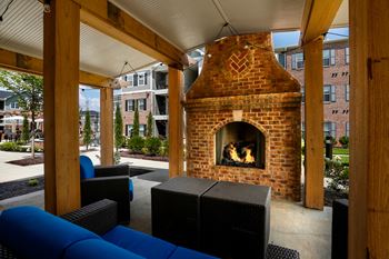 Outdoor fireplace and seating with blue cushions under pergola