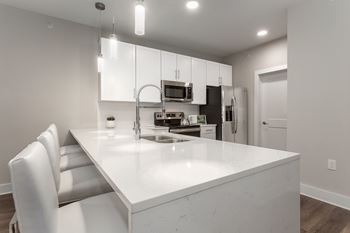 Kitchen inside an apartment home with white cabinets, quartz countertops and stainless steel appliances