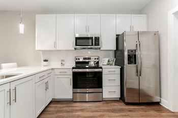 A white kitchen with stainless steel appliances and white cabinets