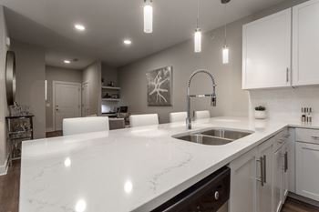 An open kitchen with white counter tops and a sink
