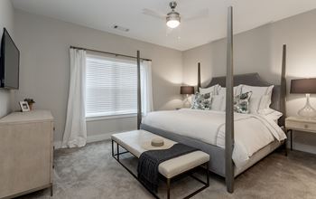 A bedroom with a bed and a table in front of a window