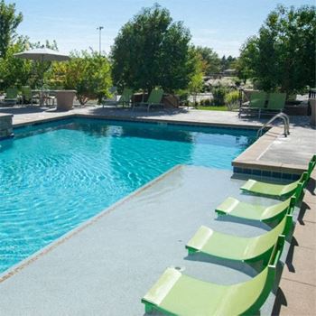 A swimming pool with green chairs 