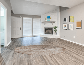 An empty living room with a rug and a fireplace