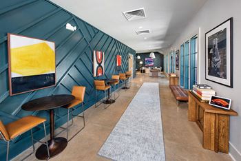 A lobby with tables and chairs and a blue wall with paintings