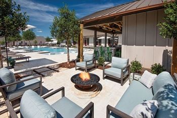 A fire pit on a patio next to a swimming pool
