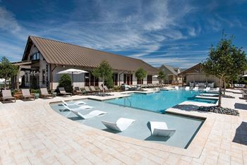A large swimming pool with lounge chairs and a building
