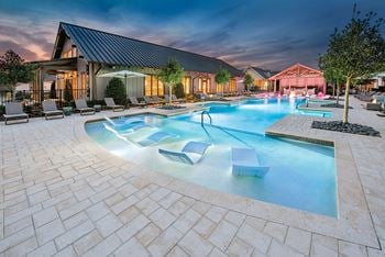 A large swimming pool with lounge chairs and a building in the background