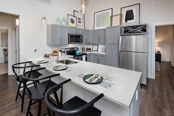 A kitchen with a white counter top and black chairs.