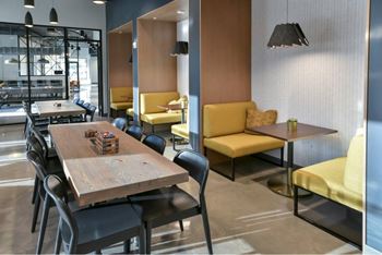 A modern dining area with wooden tables and black chairs.