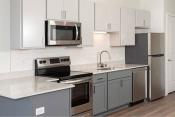 A modern kitchen with a stove, oven, microwave, and refrigerator.