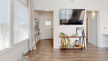A room with a wooden floor and a white wall with a painting on it.