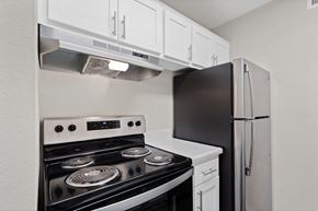 Tucson apartment for rent - Kitchen with white cabinets and black appliances and a refrigerator at Agave Apartments, Tucson, AZ
