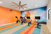 Tucson apartment for rent - Gym with exercise bikes and a mural of a man riding a bike at Verde Apartments in Tucson, AZ.