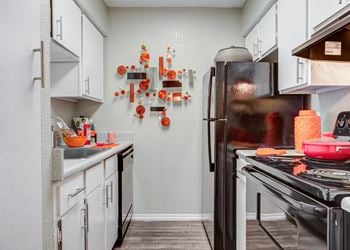 Kitchen with white cabinets and black appliances at the enclave