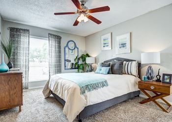 A bedroom with a large bed and a ceiling fan