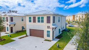 Mount Dora apartment for rent - A white house with a brown garage door is surrounded by a green lawn.