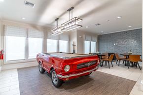 Lady Lake apartment for rent - A red vintage car is parked in a spacious room with a dining table and chairs.