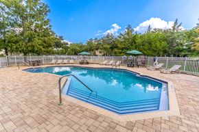 Lady Lake apartment for rent - a resort style pool with chairs and umbrellas in a yard with trees