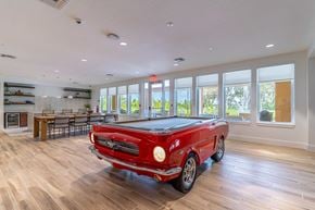 Mount Dora apartment for rent - A red vintage car is parked in a spacious room with wood flooring and large windows.
