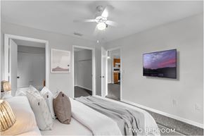 Orlando apartment for rent - A bedroom with a bed, pillows, a ceiling fan, and a painting on the wall.