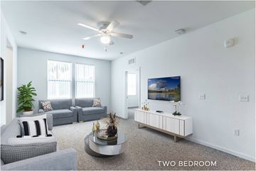 Palm Coast apartment for rent - A living room with a grey couch, a white armchair, a coffee table, and a painting on the wall.