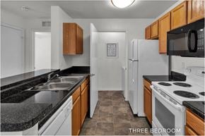 Orlando apartment for rent - A kitchen with a white refrigerator and black countertops.