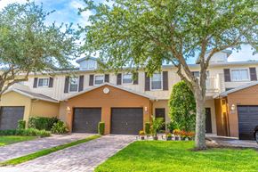 Kissimmee townhouse for rent - a townhome with two garages and a tree in front of it