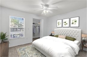 Tampa apartment for rent - A bedroom with a large bed, a ceiling fan, and a window with a view of trees.
