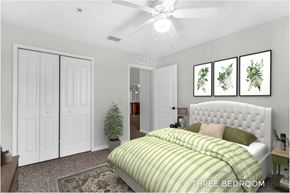Kissimmee apartment for rent - A bedroom with a bed, a ceiling fan, and a wall hanging with three framed plants.