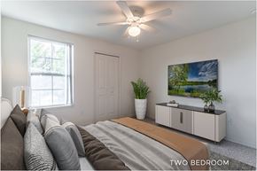 Fern Park apartment for rent - A bedroom with a bed, pillows, a ceiling fan, and a painting on the wall.