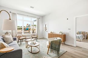 South Dartmouth apartment for rent - A living room with a grey sofa, a wooden coffee table, and a large window with a view of the outside.