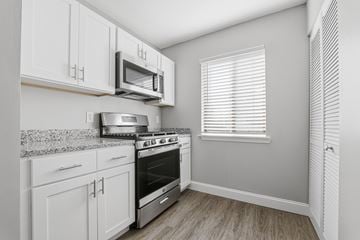 New Bedford apartment for rent - A kitchen with white cabinets and a stainless steel stove and microwave.
