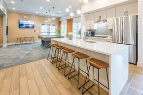 Bridgewater apartment for rent - A modern kitchen with a long white counter and bar stools at Axis at Lakeshore Apartments, Bridgewater, Massachusetts, 02324