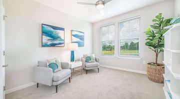 Charleston apartment for rent - A living room with two grey couches, a ceiling fan, and two paintings on the wall.