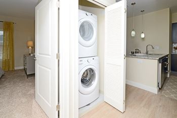 A white door is open to a laundry room and a kitchen