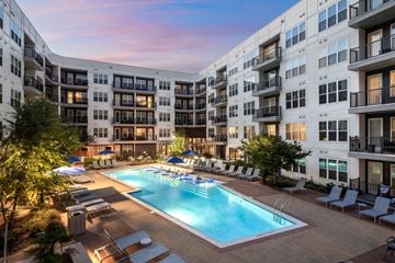 Atlanta apartment for rent - A large swimming pool surrounded by lounge chairs and umbrellas in front of apartment buildings.
