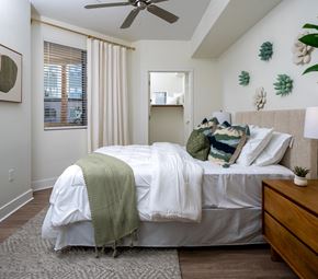 Phoenix apartment for rent - A bedroom with a bed covered in a white comforter and a green throw blanket.