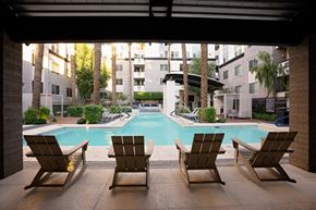 Phoenix apartment for rent - Three lounge chairs are positioned in front of a pool.