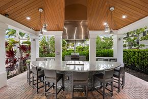 Pembroke Pines apartment for rent - A modern outdoor dining area with a glass table surrounded by chairs.