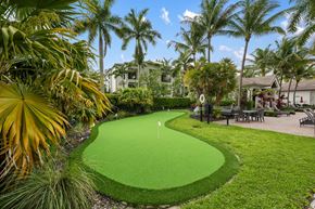 Pembroke Pines apartment for rent - A green putting green in the middle of a grassy area with palm trees.